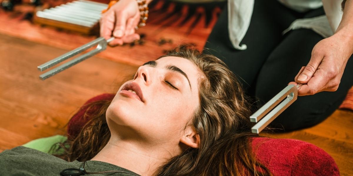 women is doing tuning fork sound healing therapy